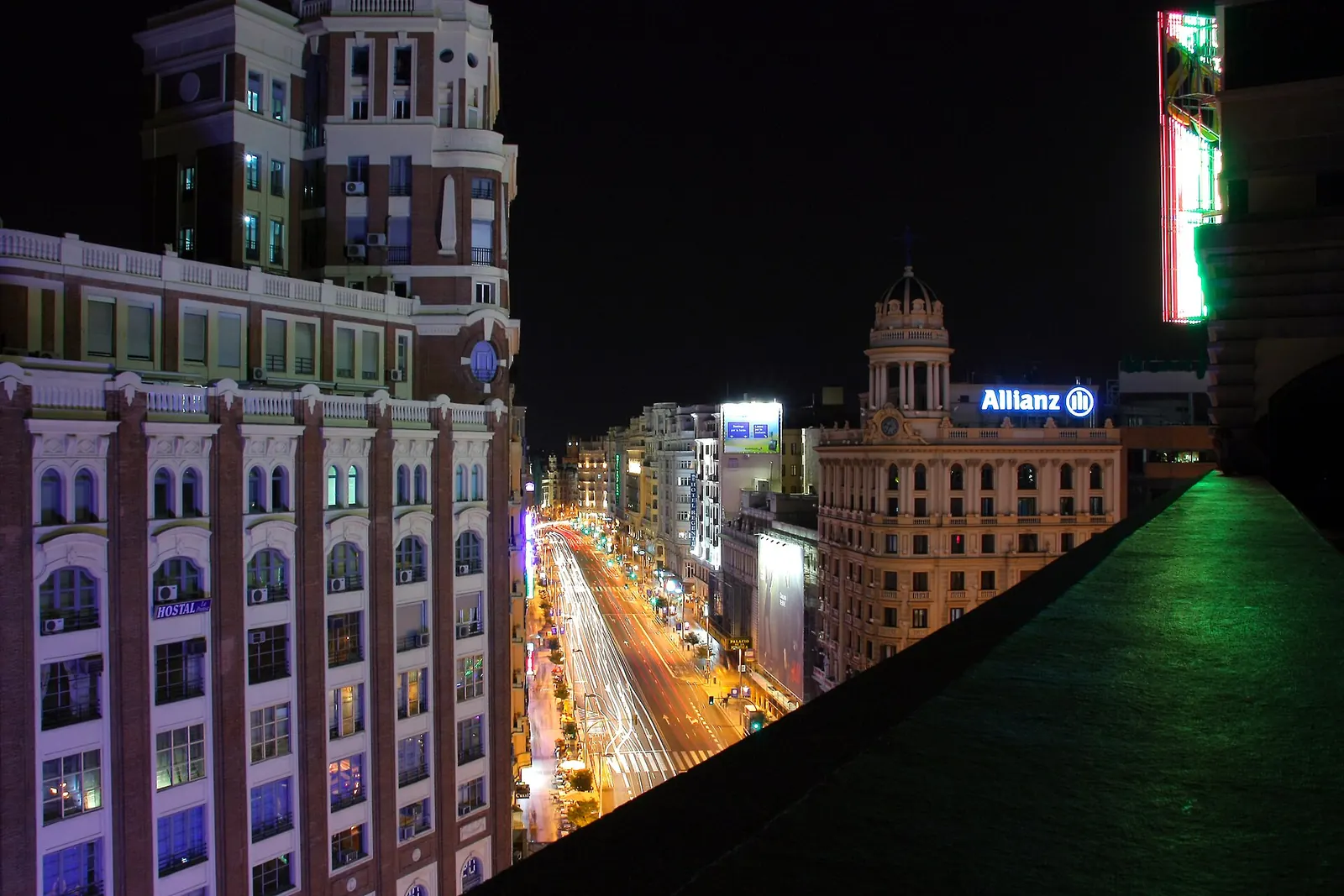 Night view down Gran Vía in Madrid from a rooftop, with lit buildings and streaks of car headlights along the avenue